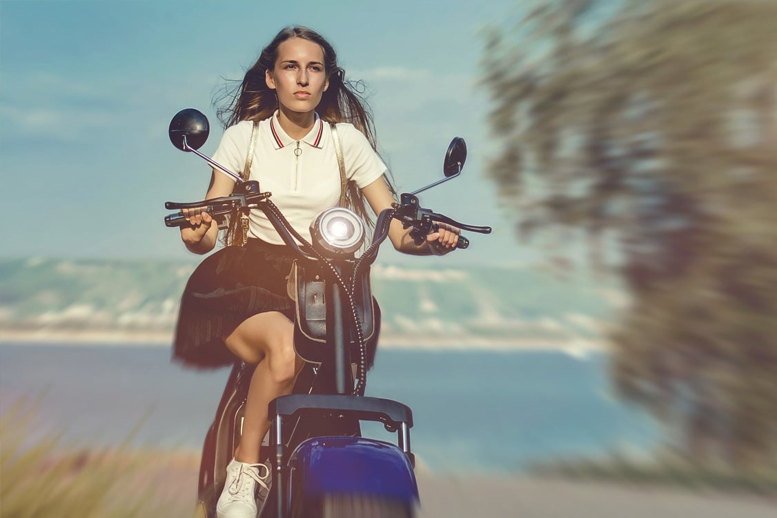 Frau fährt auf einem E-Roller Frau fährt auf einem E-Roller