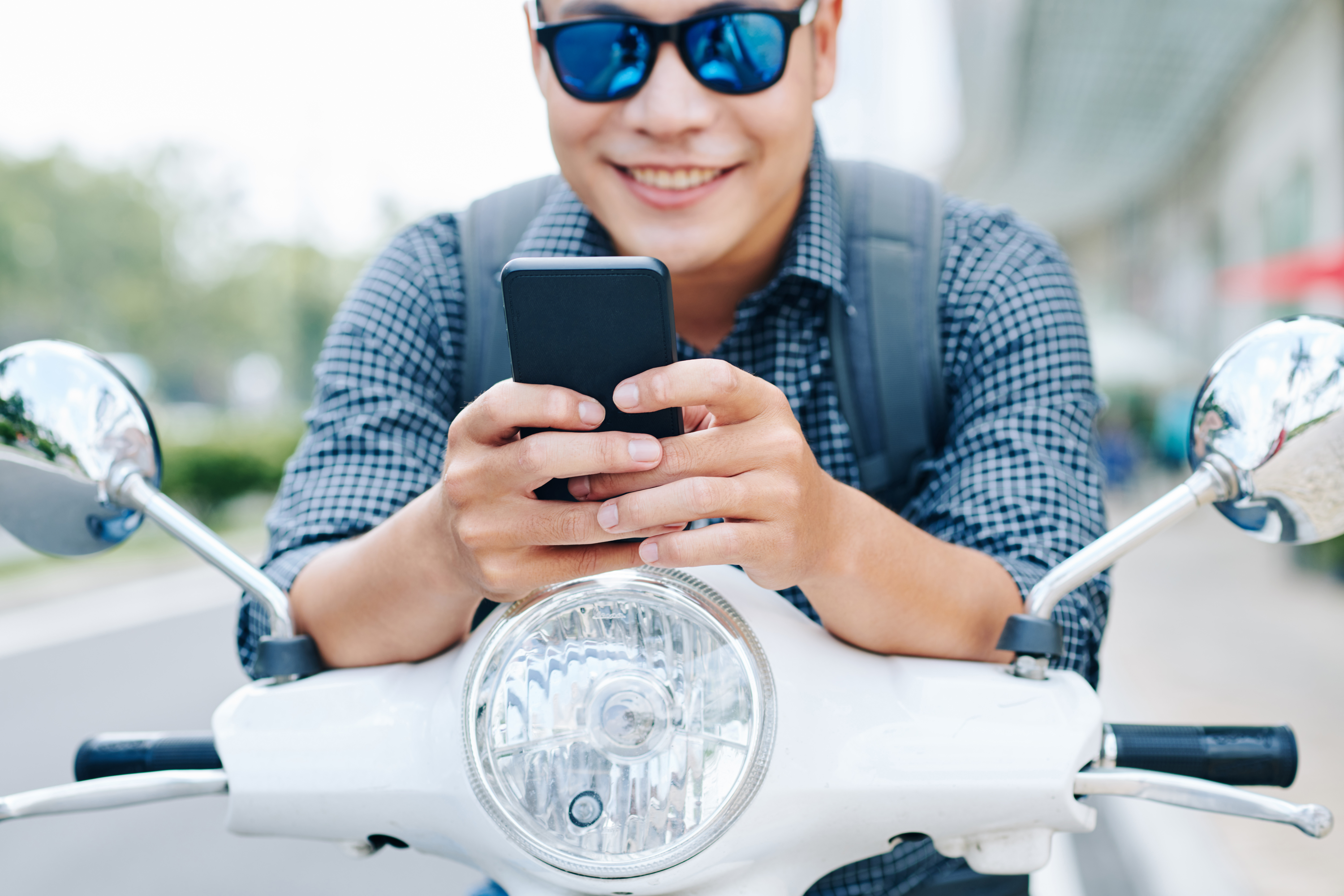 Man sitting on an e-scooter with a smartphone in his hands